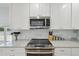 Modern kitchen features stainless steel appliances, white cabinets, and a stylish tile backsplash at 11360 Irma Dr, Northglenn, CO 80233