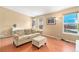 Cozy living room features a comfortable sofa, ottoman, hardwood flooring, and a bright window at 12418 Albion St, Thornton, CO 80241