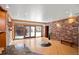 Bright living area featuring brick accent wall, wooden floors, sliding glass doors to the outdoor, and unique accents at 8280 Queen St, Arvada, CO 80005