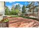 Spacious brick patio in a lush backyard with mature trees and a wooden fence at 2246 Mountain Sage Dr, Highlands Ranch, CO 80126
