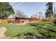 Backyard featuring lush green lawn, brick home, wooden fence, and a pergola at 3130 S Krameria St, Denver, CO 80222