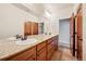 Bright bathroom with granite countertops, dual sinks, wood cabinets and travertine-style flooring at 1890 Bel Lago Vw, Monument, CO 80132