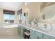 Well-lit bathroom with double vanity, makeup counter, an oval mirror, and a large window overlooking the neighborhood at 8196 Wetherill Cir, Castle Pines, CO 80108