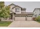 Charming two-story home featuring a three-car garage and welcoming front porch with stone accents at 8317 Liverpool Cir, Littleton, CO 80125