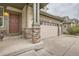 Inviting front porch with stone pillars leading to a front door and a three-car garage at 8317 Liverpool Cir, Littleton, CO 80125