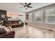 Open-concept living room with a large leather couch, ceiling fan, and hardwood floors connects to kitchen at 8317 Liverpool Cir, Littleton, CO 80125