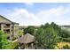 View from the condo balcony of the community gazebo, green space and treeline under a cloudy blue sky at 8489 Canyon Rim Cir # 302, Englewood, CO 80112