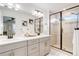 Bright bathroom with double vanity, decorative mirror, and glass enclosed shower at 431 Courtfield Way, Castle Pines, CO 80108