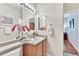 Bright bathroom vanity features a sink, neutral countertop, wood cabinets, floral decor, and a large mirror at 4385 Oakes Mill Ct, Castle Rock, CO 80109