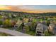 Sunset view of home exteriors in neighborhood nestled amongst trees and rolling mountains at 24005 High Meadow Dr, Golden, CO 80401