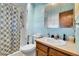 A well-lit bathroom featuring a shower with a curtain and a wooden vanity sink at 12317 Fillmore Ct, Thornton, CO 80241