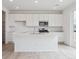 Bright kitchen with white cabinets, stainless steel appliances, a large island, and wood-style flooring at 24777 E 40Th Ave, Aurora, CO 80019