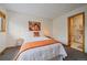Bright bedroom with white linens and a pop of color from an orange throw and adjacent bathroom at 9200 E Cherry Creek South Dr # 10, Denver, CO 80231