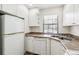 Efficient kitchen features white appliances, ample cabinet space, and a stainless steel sink under a bright window at 16104 E Alaska Pl # D, Aurora, CO 80017