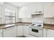 Kitchen features white appliances, laminate countertops, and ample natural light from the window at 16104 E Alaska Pl # D, Aurora, CO 80017