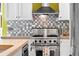 Close-up of stainless steel gas range, vent hood, tiled backsplash, and a colorful kitchen towel at 1435 Wazee St # 504, Denver, CO 80202