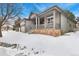 Gray home with a covered porch, brick foundation, and snowy yard, offering curb appeal at 2112 Springs Pl, Longmont, CO 80504