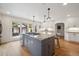 Spacious kitchen features a gray island with granite counters, stainless gas cooktop, hardwood floors, and white cabinets at 1016 S Cook St, Denver, CO 80209