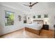 Bright main bedroom with light hardwood floors, tray ceiling with ceiling fan, and three windows at 1016 S Cook St, Denver, CO 80209