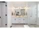 Bathroom with double vanity, white cabinets, large mirror, and a walk-in shower at 8768 E 54Th Pl, Denver, CO 80238