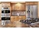 Kitchen boasts stainless steel appliances, gas stove top and double wall ovens with wood cabinets at 9001 Eastridge Rd, Golden, CO 80403