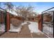Inviting gated front yard with a walkway leading to the entrance, bordered by well-kept landscaping and snow at 536 Detroit St, Denver, CO 80206
