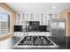 A well-equipped kitchen with a stove-top island, stainless steel appliances, and bright white cabinetry at 536 Detroit St, Denver, CO 80206