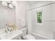 Bright bathroom with a white sink, toilet, tub, shower, subway tile, and a black and white view out the window at 165 N High St, Denver, CO 80218