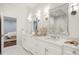 Bright bathroom with dual sinks, stone countertops, decorative mirrors, and views of a bedroom in the background at 165 N High St, Denver, CO 80218