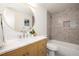 Bathroom featuring a round mirror, wooden vanity, and tiled shower at 8422 Everett Way # D, Arvada, CO 80005