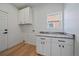 Bright laundry room with white cabinets, granite countertops, and wood floors at 5586 S Harlan St, Littleton, CO 80123