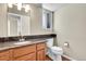 Bathroom featuring wooden cabinets, granite countertop, updated fixture, and modern toilet at 9008 W 101St Ave, Broomfield, CO 80021