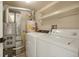 Functional laundry room with washer, dryer, utility equipment, and shelving at 12593 E Pacific Cir # E, Aurora, CO 80014
