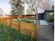Backyard view of a putting green, detached building, wooden fence, and mature trees at 9380 W 51St Ave, Arvada, CO 80002