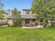 Spacious backyard with a covered patio, lush green lawn, and mature trees for shade at 3210 S Espana Cir, Aurora, CO 80013