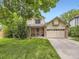 Charming two-story home featuring a well-manicured lawn, mature trees, and a two-car garage at 3210 S Espana Cir, Aurora, CO 80013