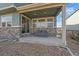 View of a cozy back porch with stone accents and covered chairs, perfect for outdoor relaxation at 27185 E Costilla Dr, Aurora, CO 80016