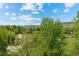 Scenic backyard view featuring lush trees, a home's roofline, and mountains under a partly cloudy sky at 15904 W 58Th Ave, Golden, CO 80403