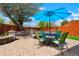 Charming backyard patio with seating area with a blue umbrella, lush landscaping, and mature trees at 4779 S Bannock St, Englewood, CO 80110
