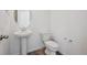 A clean half-bathroom features a pedestal sink, modern toilet, and stylish wood-look floors at 45921 Wood Thrush Ave, Bennett, CO 80102