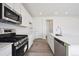 Modern kitchen boasts stainless steel appliances, white countertops and cabinets, and light wood floors at 45921 Wood Thrush Ave, Bennett, CO 80102