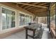Covered back porch with a large dark-stained wooden picnic table, perfect for outdoor dining at 13131 Pennsylvania St, Thornton, CO 80241
