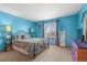 Bright bedroom with blue walls, window views, and carpet provides a comfortable space at 13131 Pennsylvania St, Thornton, CO 80241