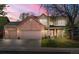 Charming two-story brick home featuring a three-car garage, covered porch, and well-maintained front yard at sunset at 13131 Pennsylvania St, Thornton, CO 80241