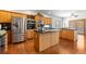 Eat-in kitchen features stainless appliances, wood cabinets, backsplash, island cooktop, and hardwood floors at 13131 Pennsylvania St, Thornton, CO 80241