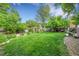 Expansive backyard with lush green lawn, mature trees, and a charming pergola seating area at 10972 Fairfax Ct, Thornton, CO 80233