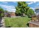 Well-manicured backyard with wooden fence, lush lawn, and mature trees at 8761 Cloverleaf Cir, Parker, CO 80134