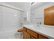 Well-lit bathroom with white tile, wood cabinets, and a shower-tub combination at 8761 Cloverleaf Cir, Parker, CO 80134