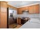 Cozy kitchen featuring stainless steel refrigerator and oven with wooden cabinets and light countertops at 8761 Cloverleaf Cir, Parker, CO 80134