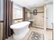Bathroom featuring a soaking tub, glass-enclosed shower, and tiled walls at 6964 S Olive Way, Centennial, CO 80112